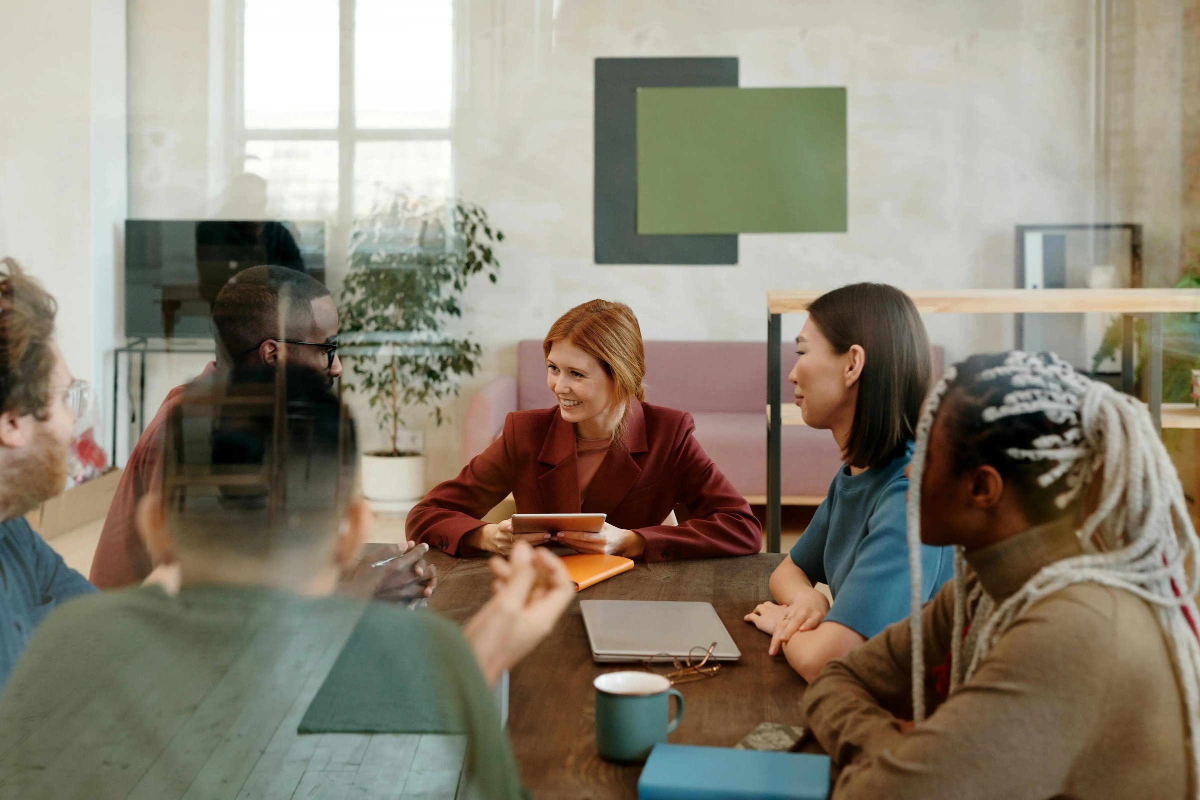 ein Team bestehend aus jungen Mitarbeiterinnen und Mitarbeitern sitzt gemeinsam an einem Tisch und erarbeitet ein Konzept